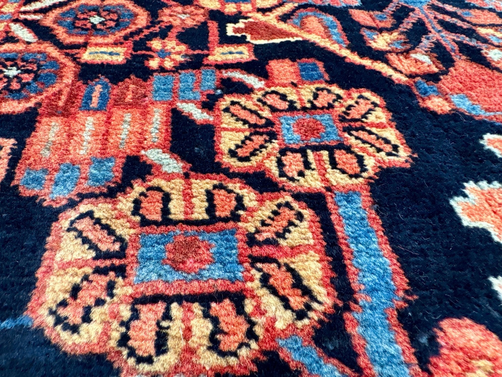 Persian Nahavand rug close-up with red-and-blue lattice and small diamond motifs.