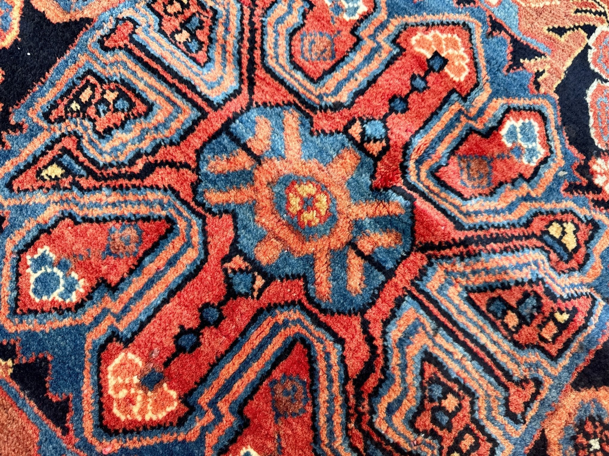 Persian Nahavand rug detail: coral and blue star medallions with navy outlines.