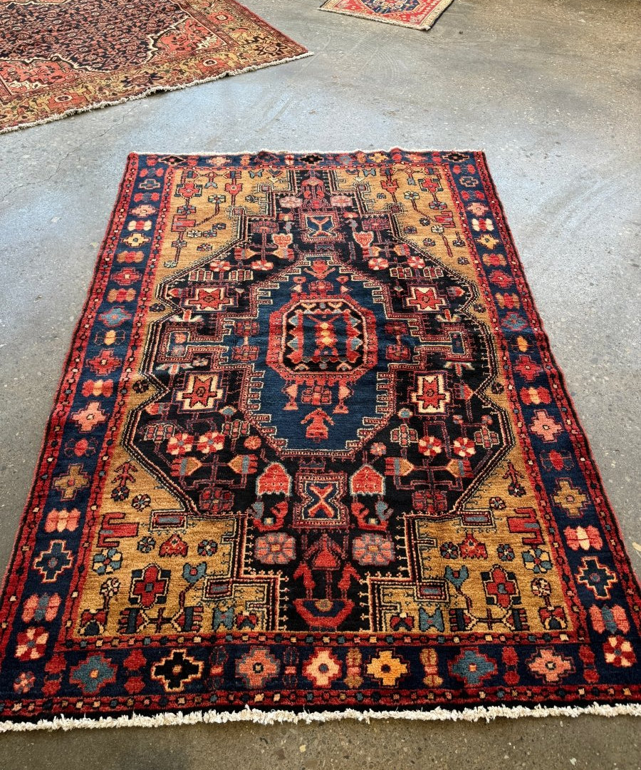 Navy Persian Nahavand rug with red border, central medallion, and geometric motifs.
