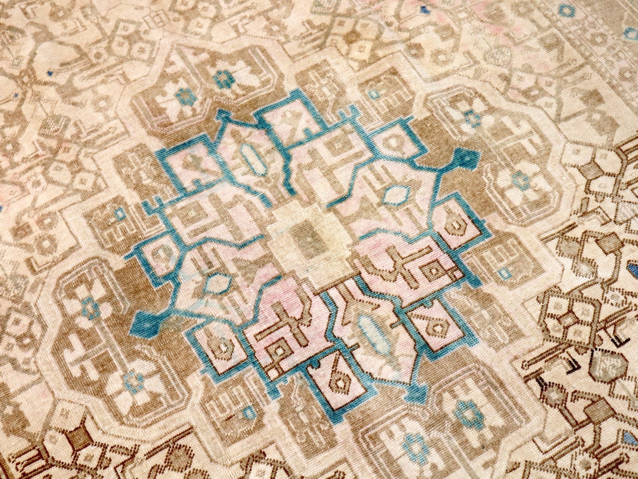 Persian rug close-up with cream ground and small blue, pink, and tan geometric forms