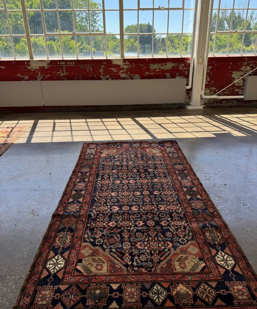 Nahavand-style Persian rug with navy center, red border, and repeating floral motifs