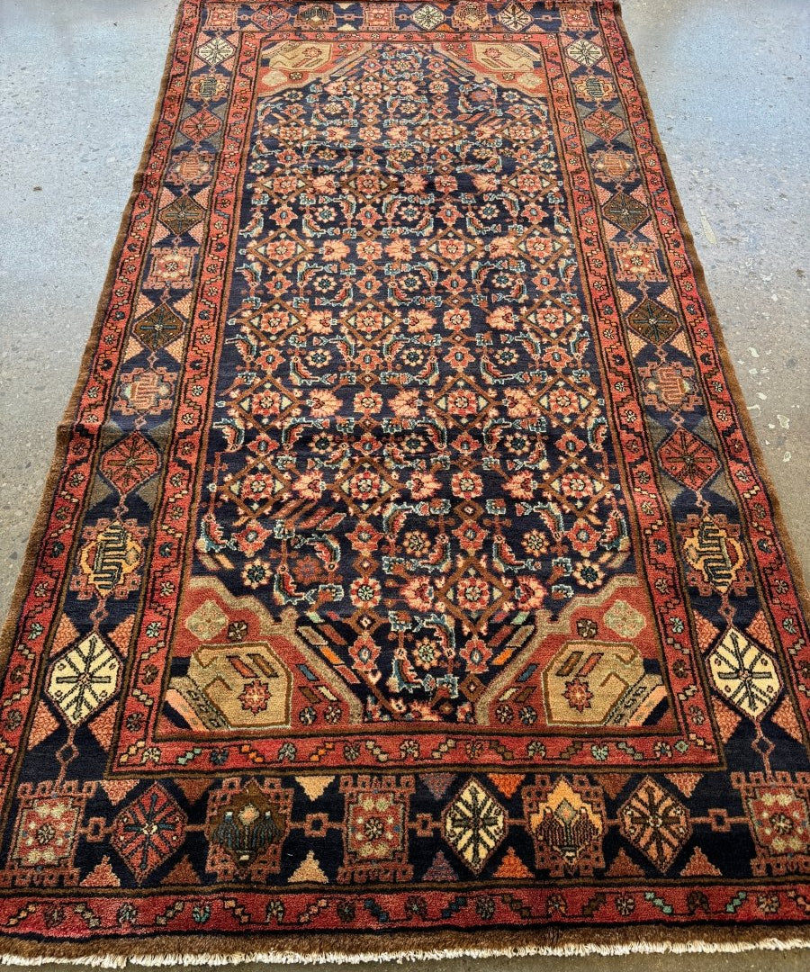 Nahavand-style Persian rug with navy field, red border, and floral medallion pattern