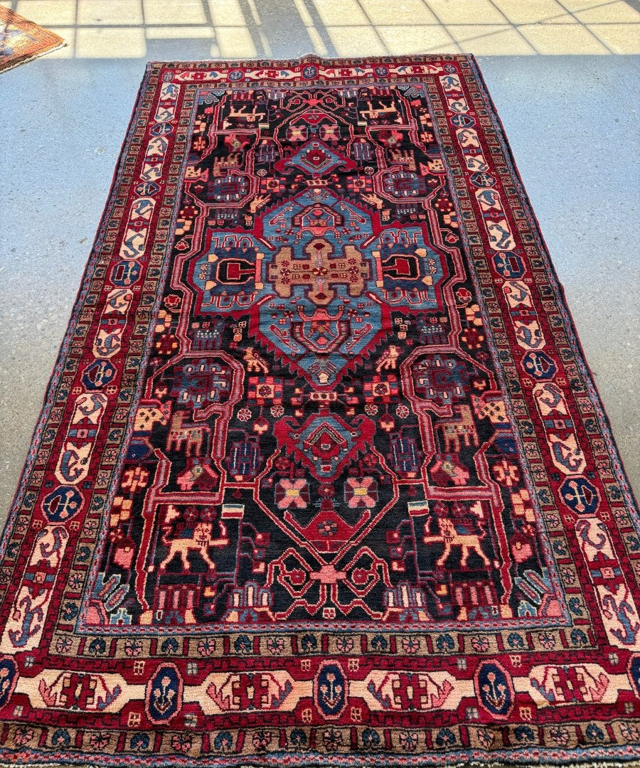 Persian area rug in navy and red with ornate medallion design and fringed border