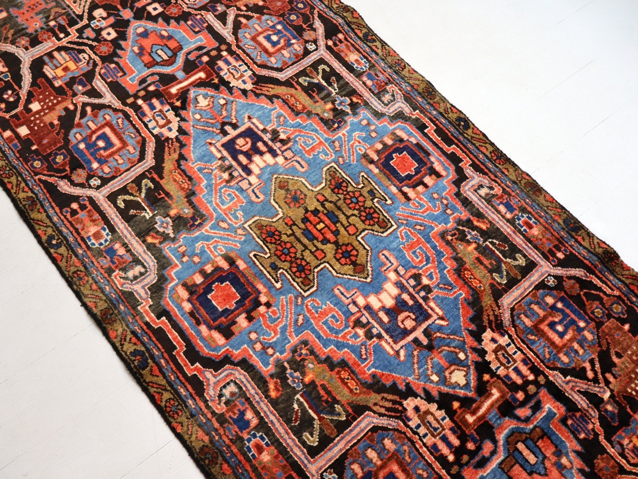 Persian runner rug close-up with blue accents, rust shapes, and intricate medallions