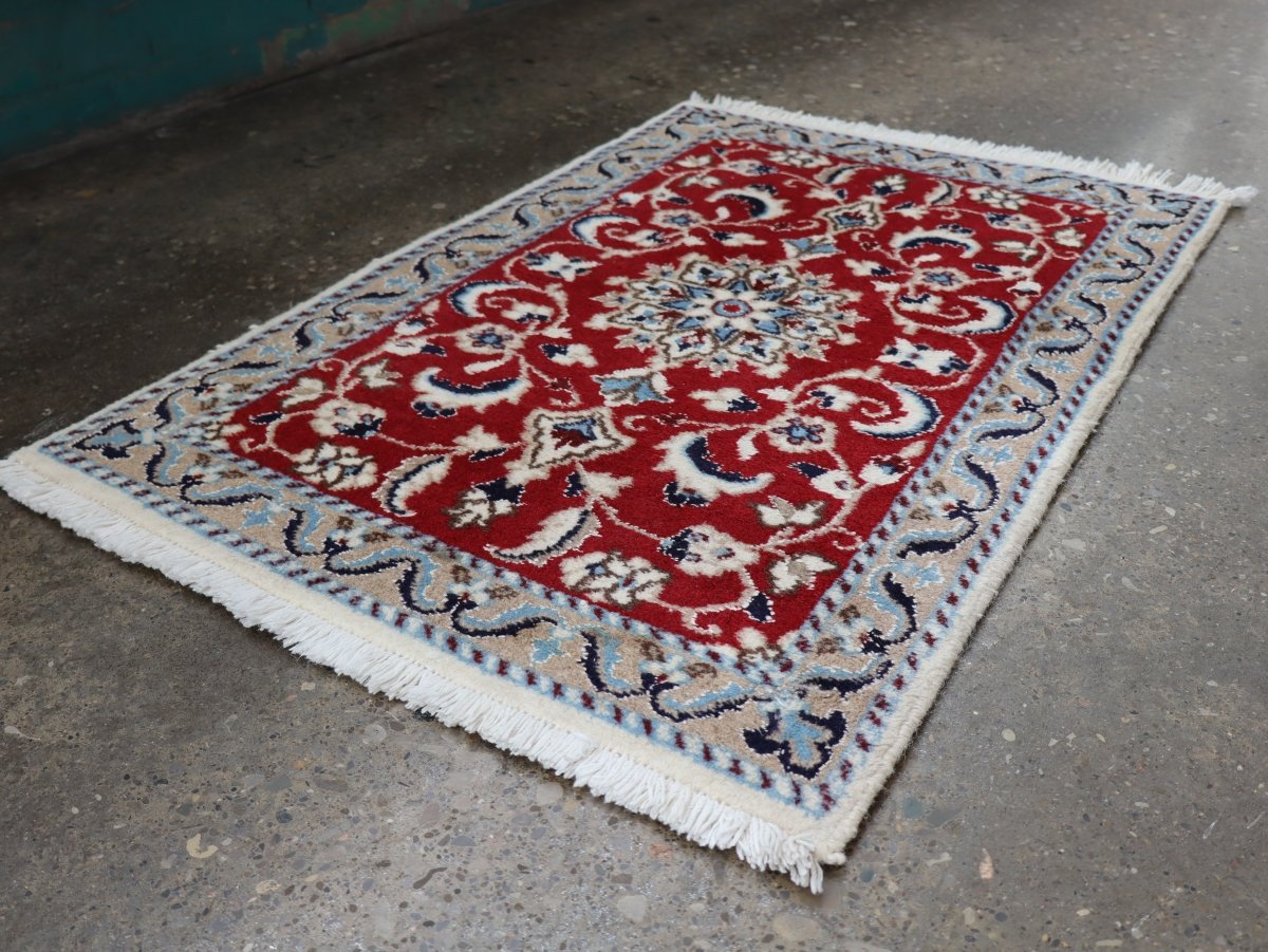 Persian Nain rug with red central medallion, blue border, cream fringe edges