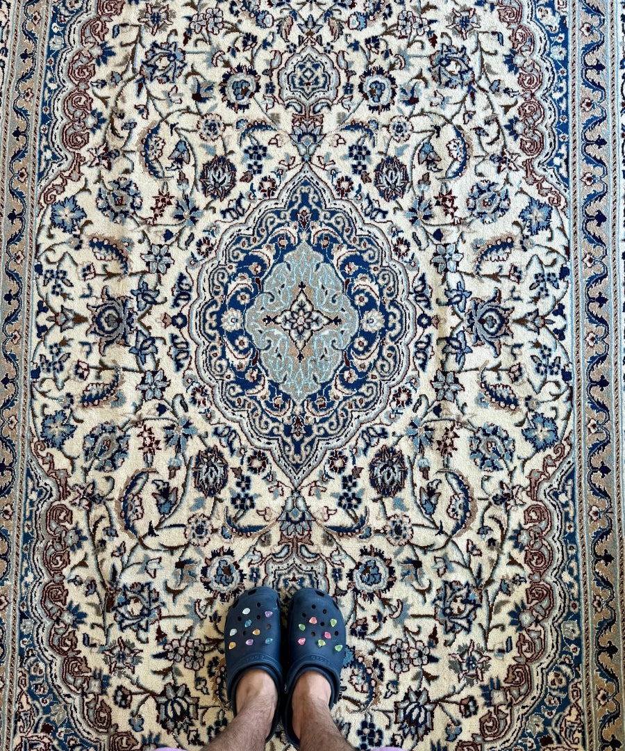 Persian-style area rug in cream with blue medallion and floral motifs