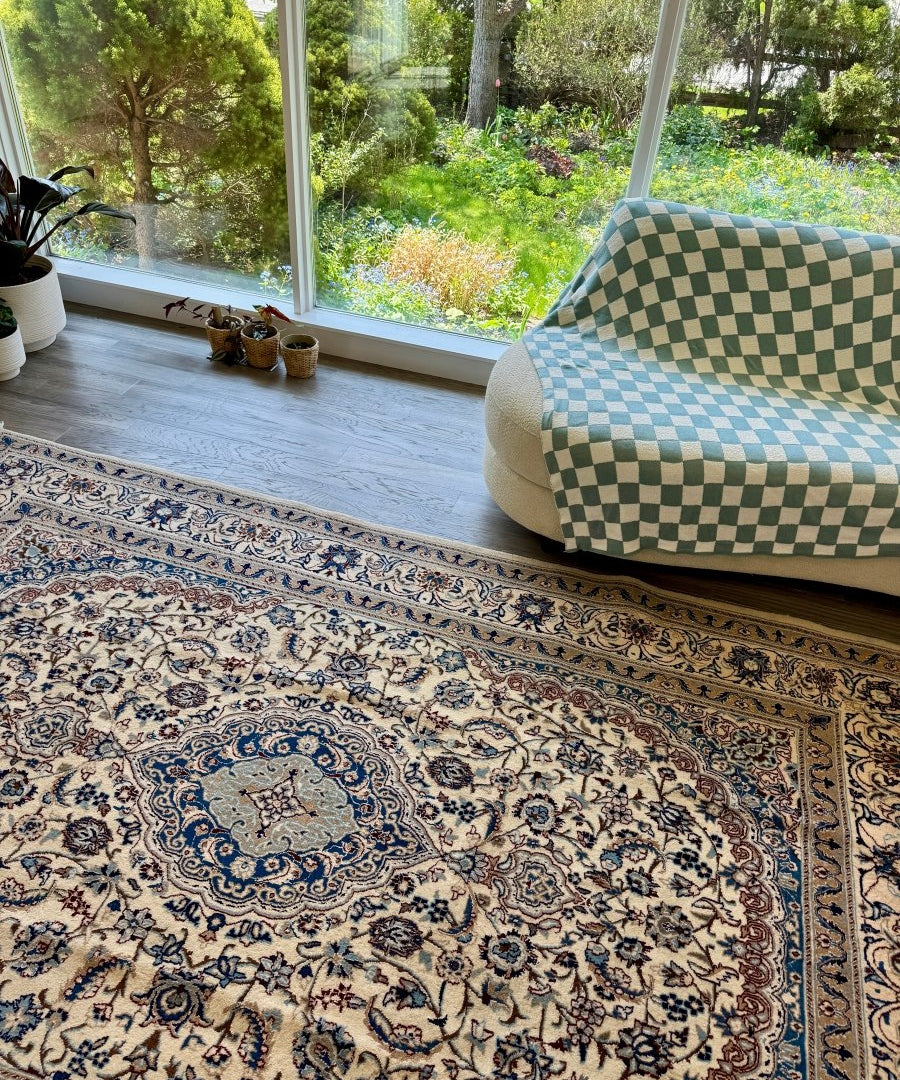 Persian-style area rug with cream field, blue floral patterns, and border