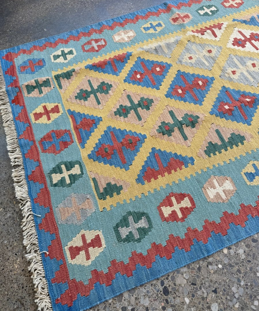 Kilim rug with diamond grid and cross symbols in blue, red and cream; fringed