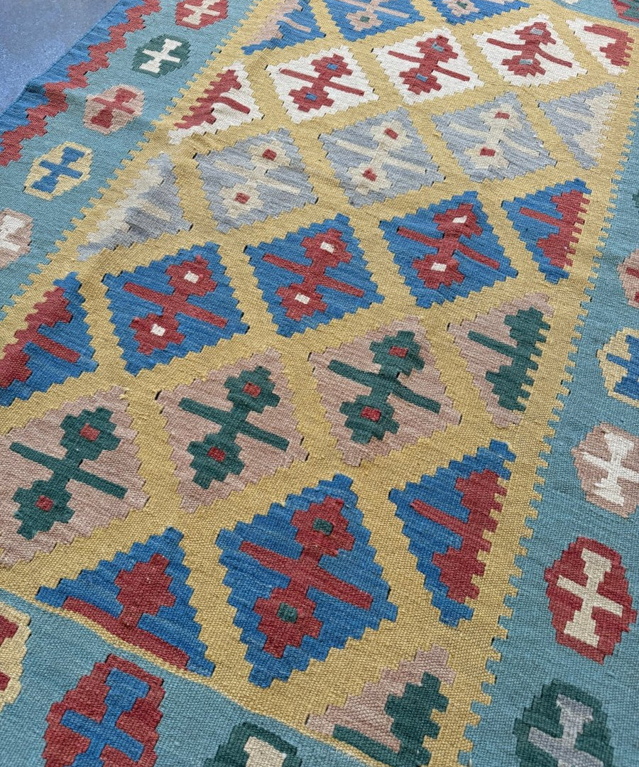 Geometric kilim rug detail with blue, beige, red, green and white cross shapes