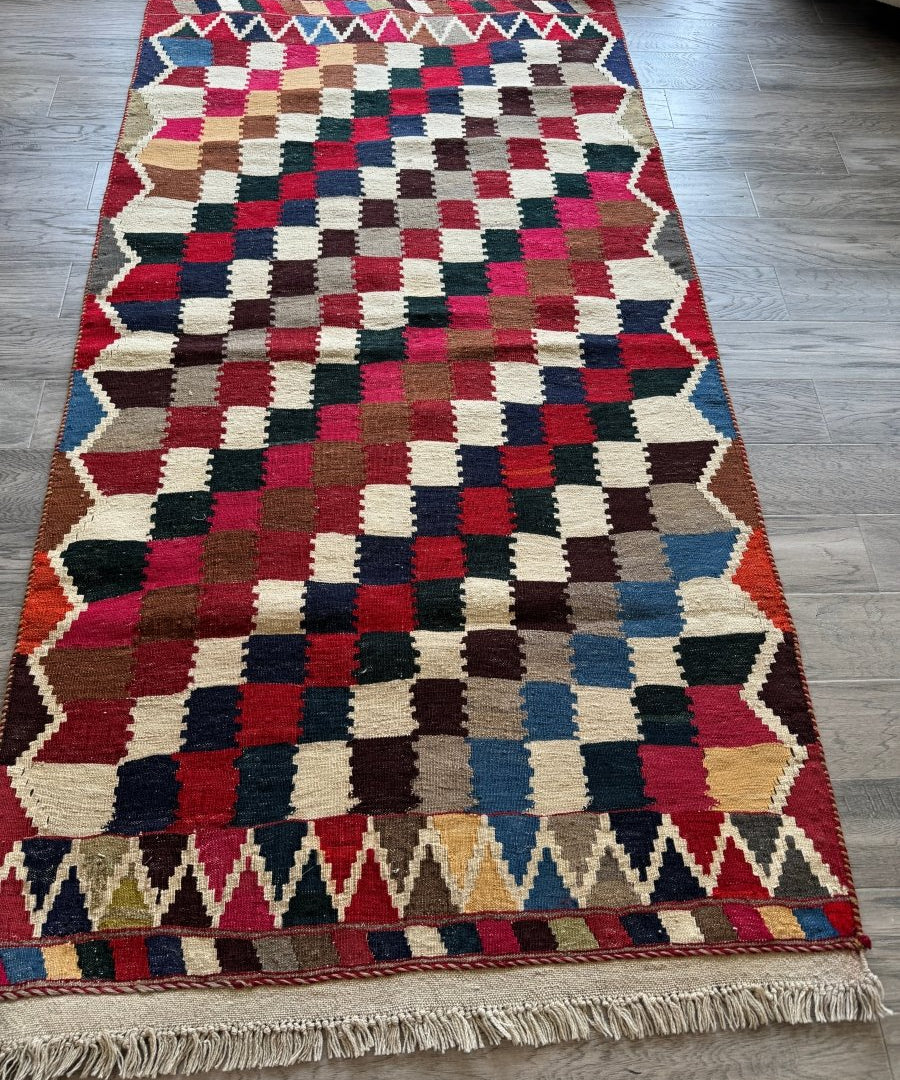 Persian Qashqai kilim rug with checkered squares and multicolor border, trimmed with fringe