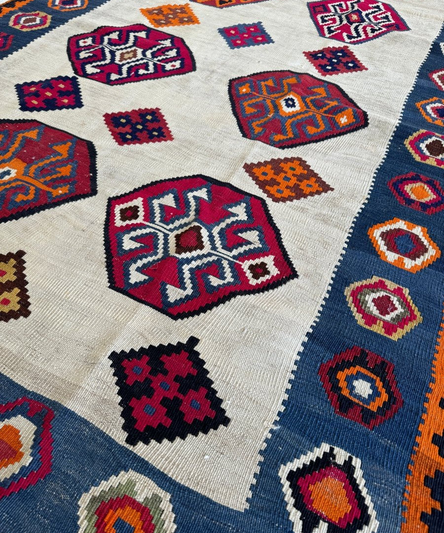 Kilim rug close-up showing cream ground with multicolor geometric squares and medallions