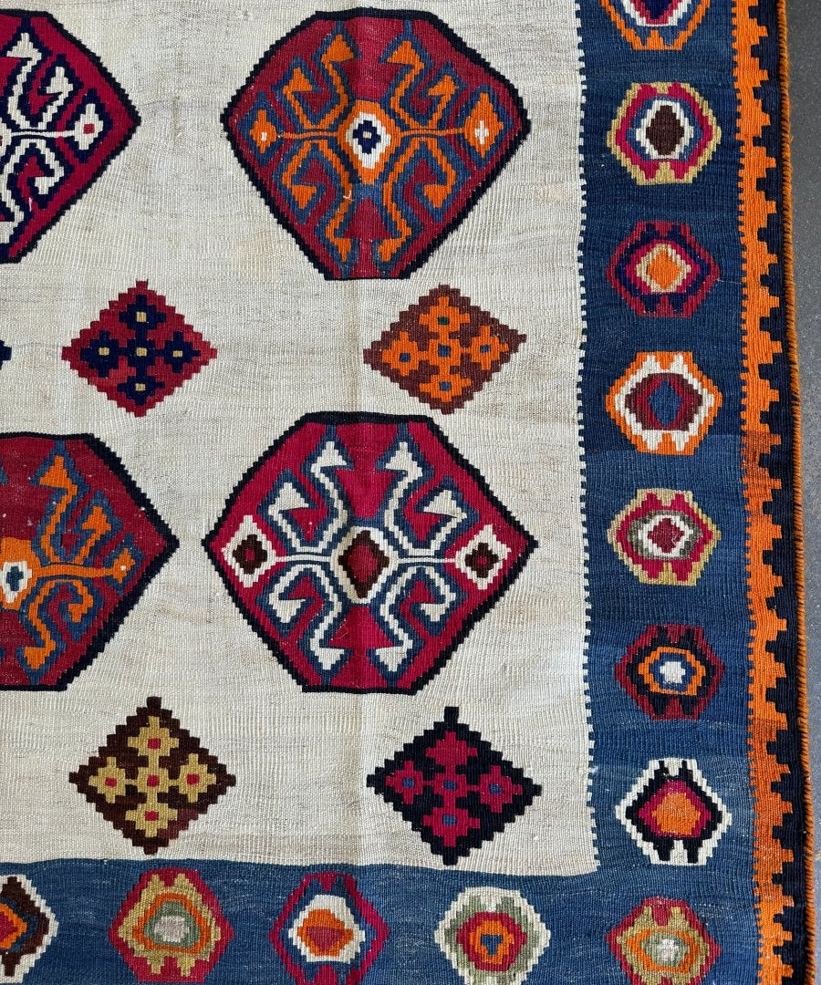 Kilim rug close-up of cream field with navy, red, and orange octagon and cross motifs