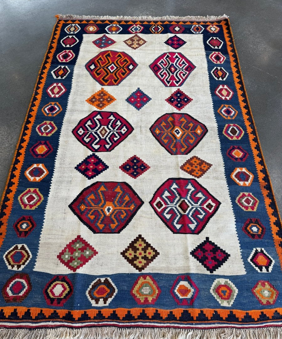 Kilim rug with cream field, navy and red diamond ornaments, orange accent border stripe
