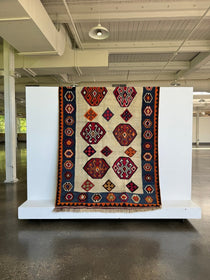 Kilim rug fully shown with cream field, navy frame, and red-orange repeating diamond motifs