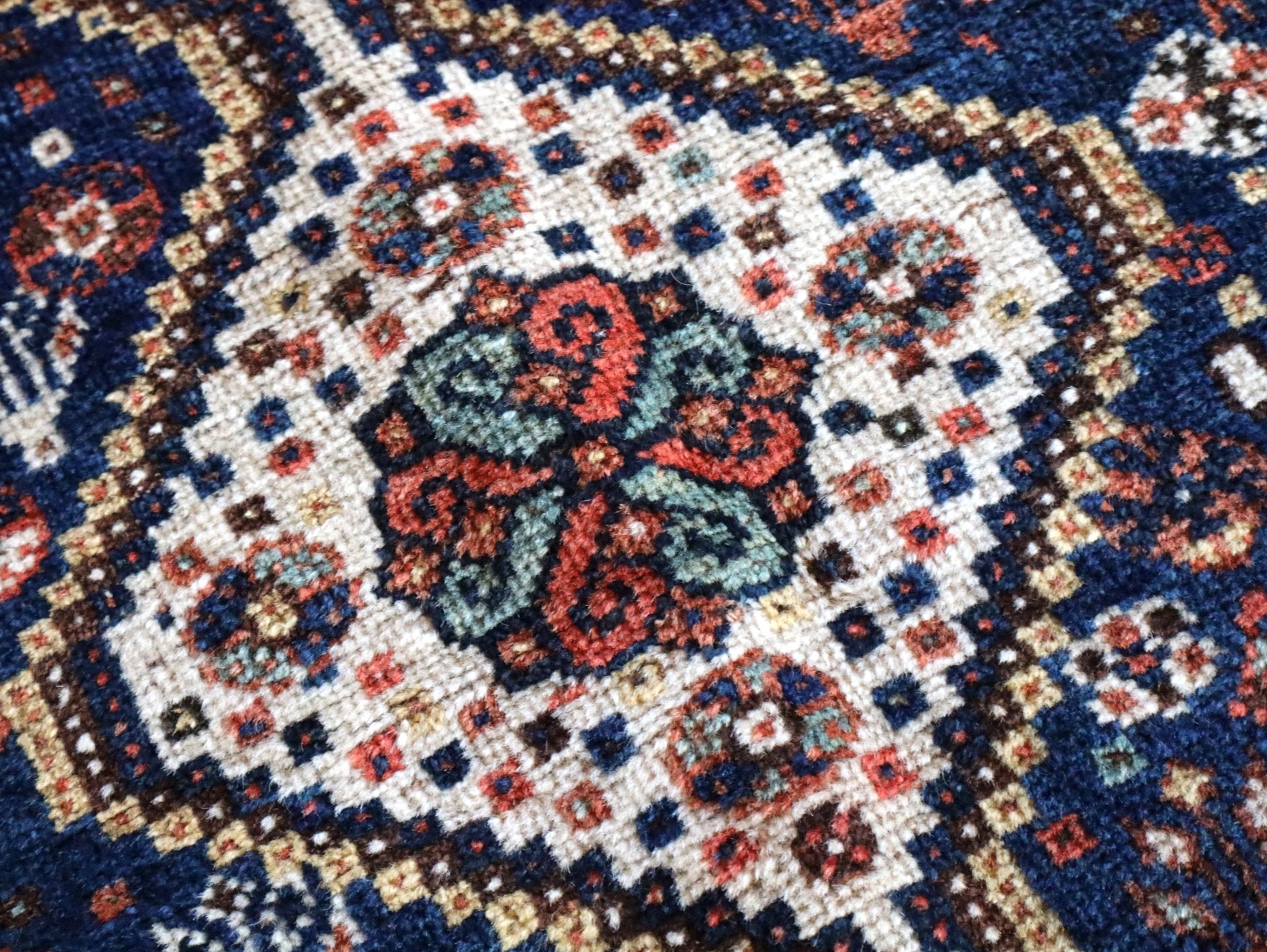 Persian Qashqai rug close-up with navy field and red cream medallion patterns