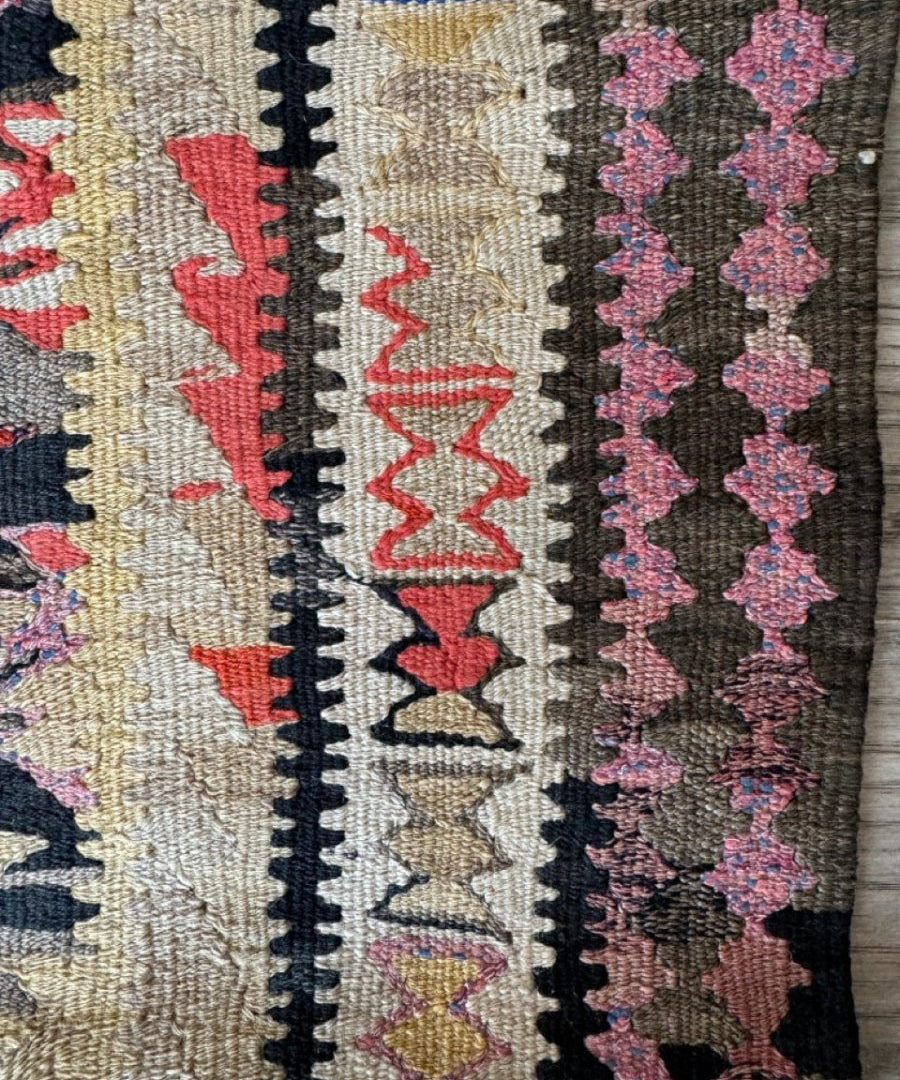 Kilim runner rug detail of striped border in cream, black, red, and pink
