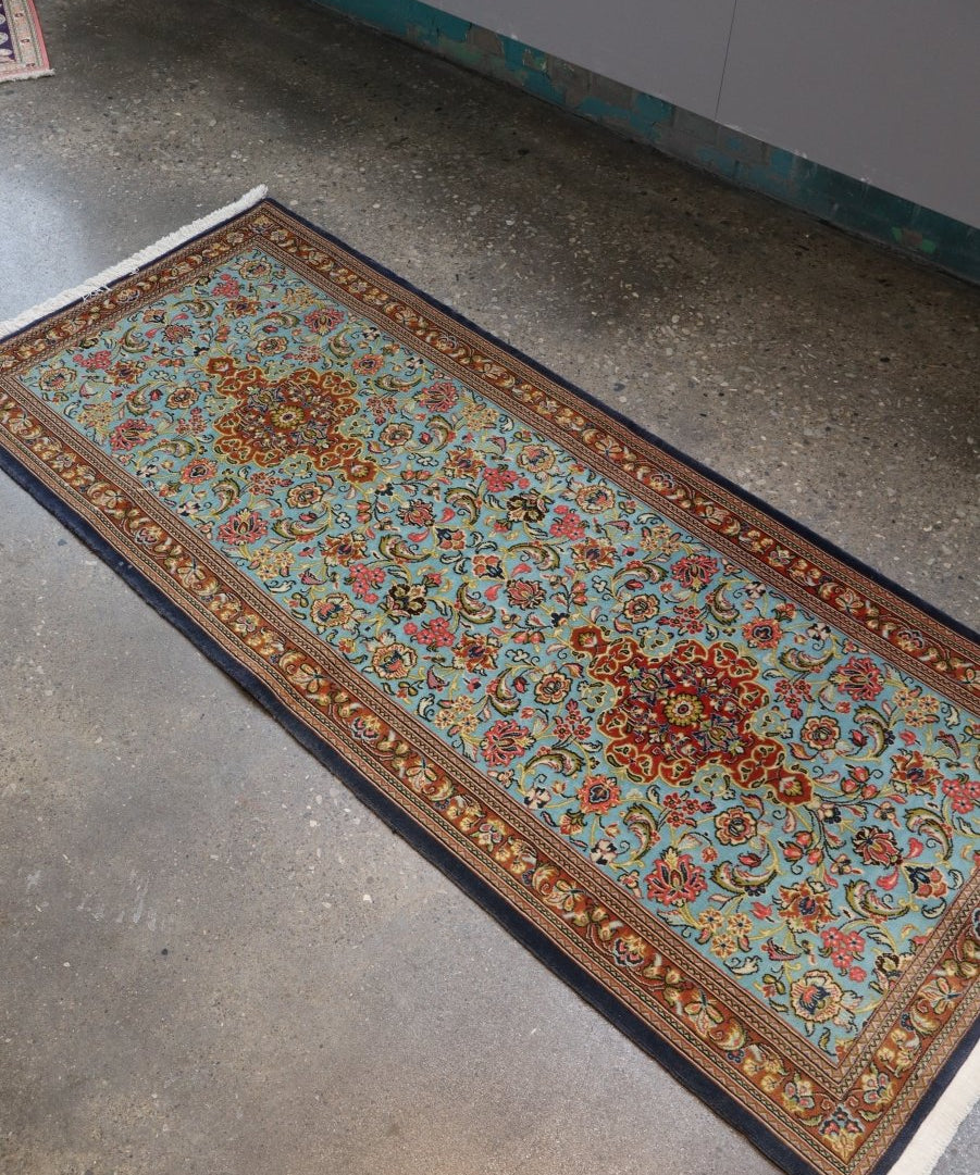 Persian wool runner rug, angled view, light blue with ornate multicolor border