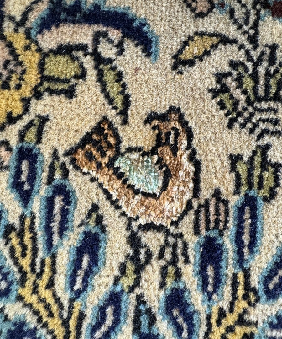 Persian Qom rug close-up, beige cream pile with blue and yellow animal details