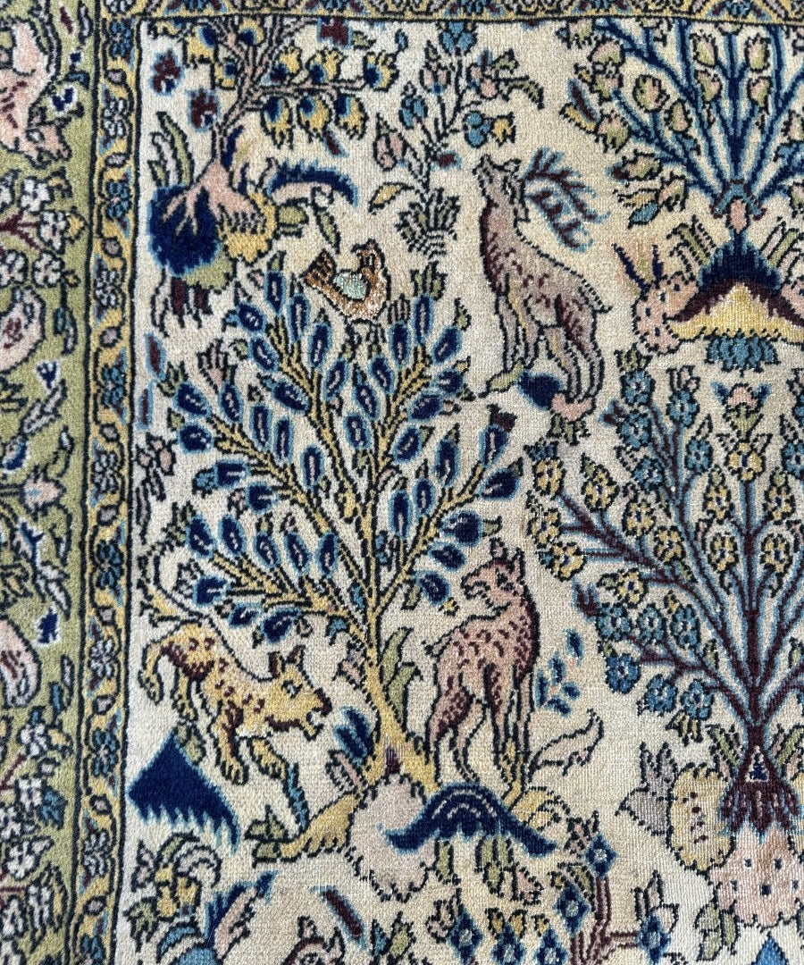 Persian Qom rug close-up, cream field with blue floral and camel figures