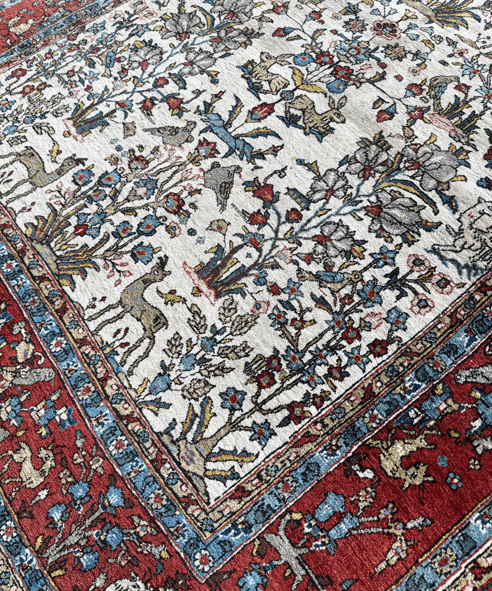 Close-up of Persian-style Qom rug pattern with colorful vines, birds, and floral details.