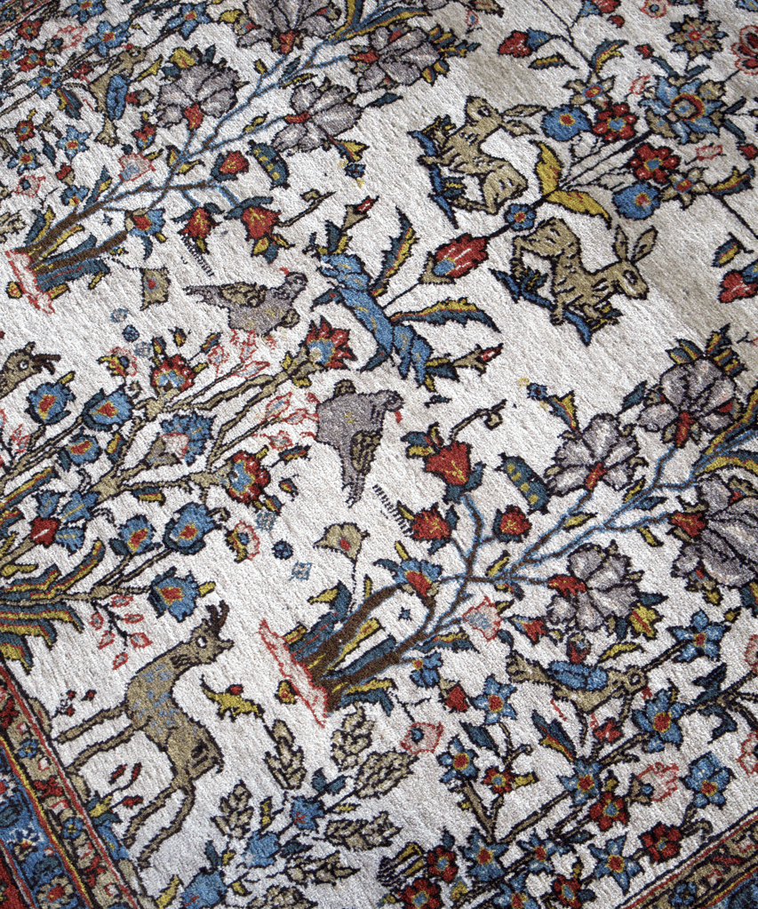 Persian Qom rug close-up, cream field with multicolor animals and flowers