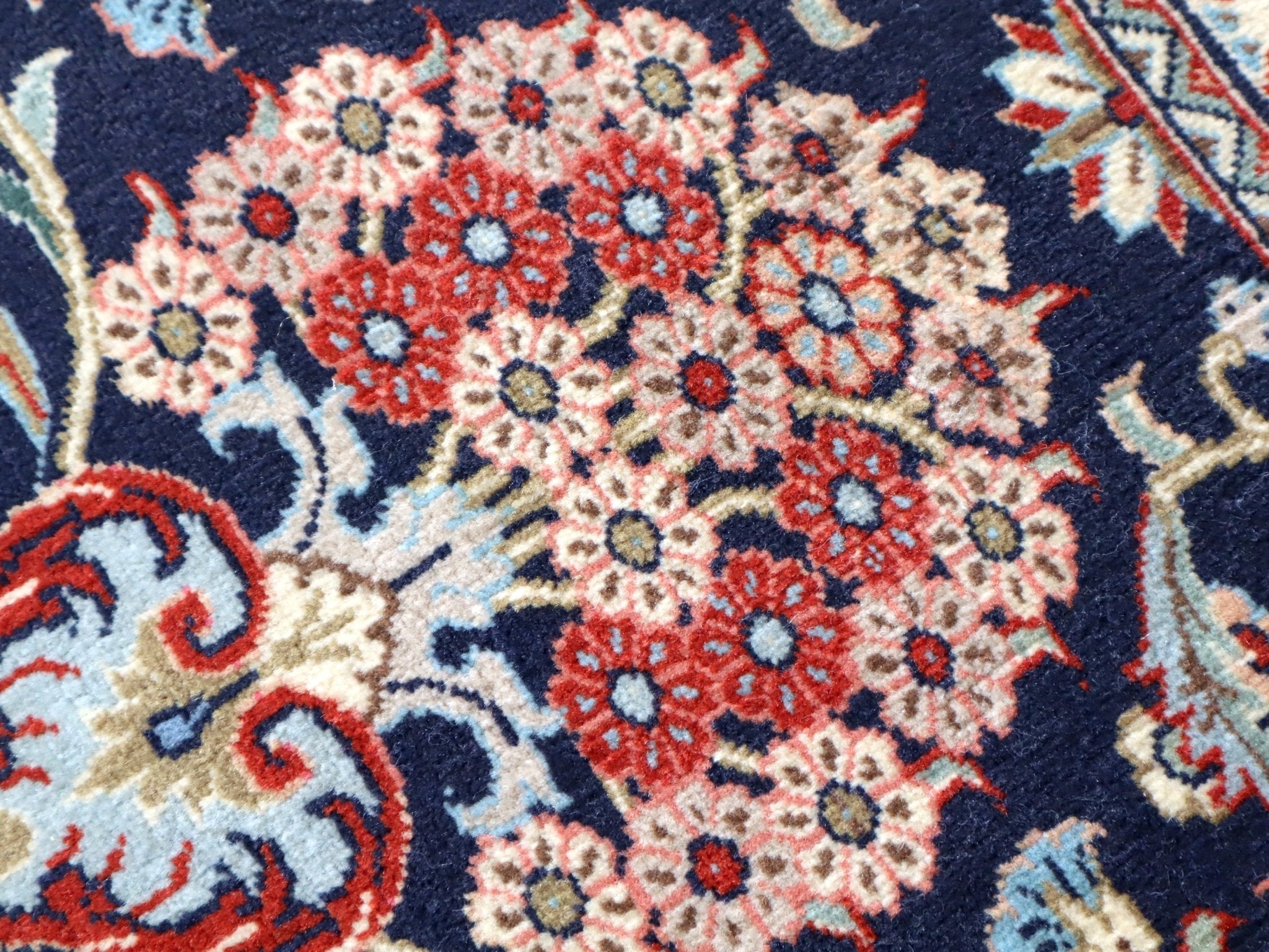 Persian Qom runner rug close-up: navy field filled with red and cream floral diamonds