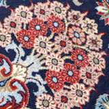 Persian Qom runner rug close-up: navy field filled with red and cream floral diamonds
