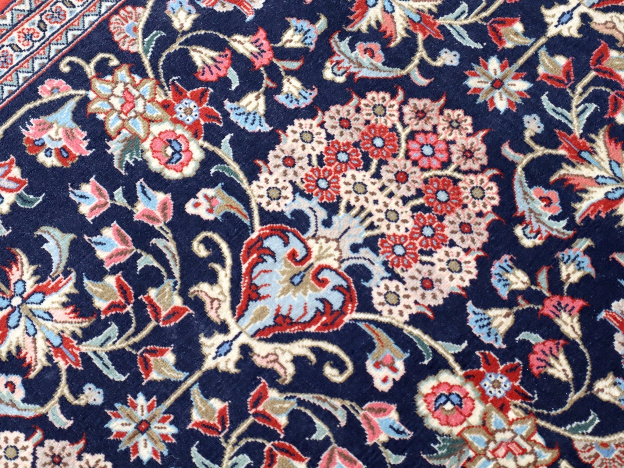 Persian Qom runner rug close-up: navy field with multicolor floral motifs and vines