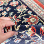 Navy Persian runner rug edge with hand-lifted fringe and red trim