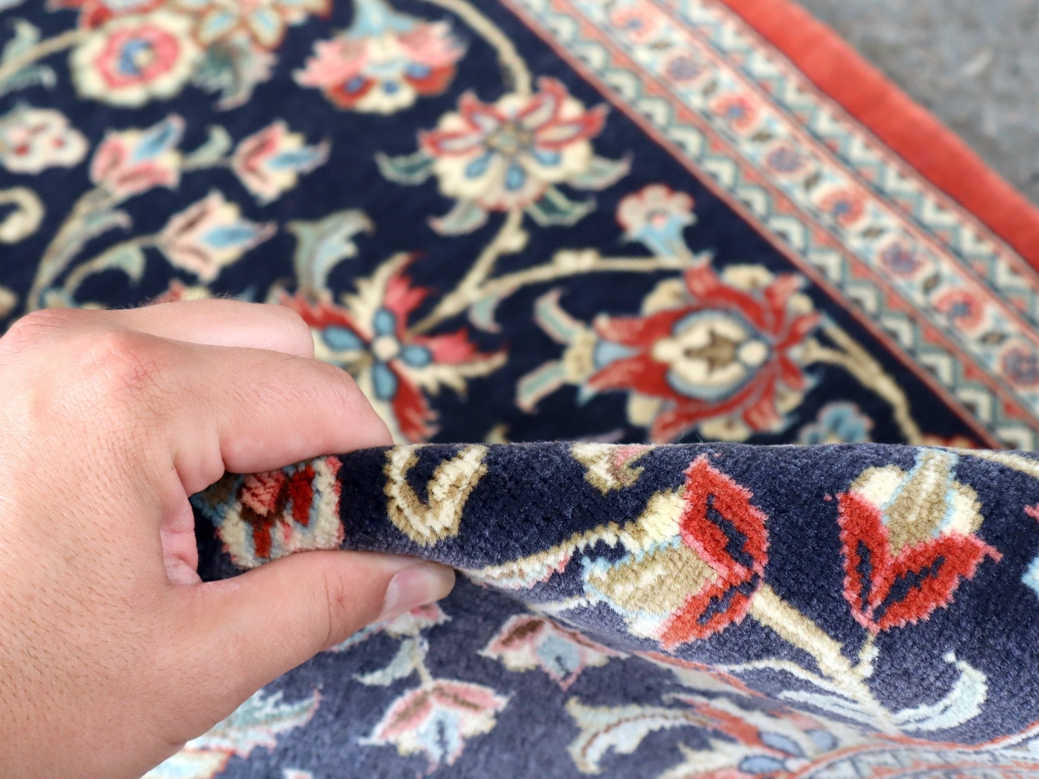 Navy Persian runner rug edge with hand-lifted fringe and red trim