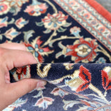 Navy Persian runner rug edge with hand-lifted fringe and red trim