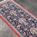 Navy Persian runner rug with red border and floral medallion pattern