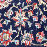 Persian Qom runner rug close-up: navy background with red, cream, and blue blossoms