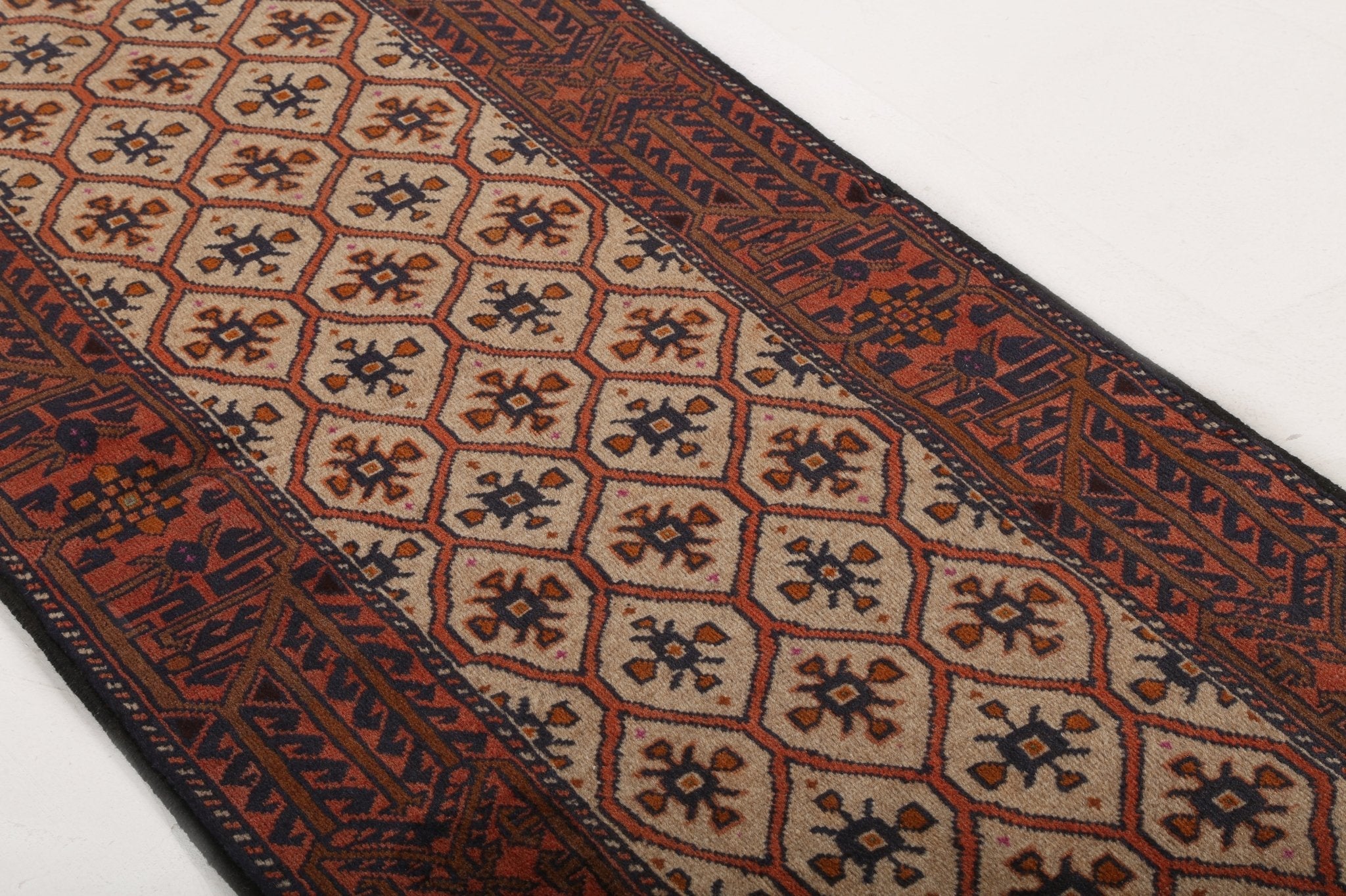 Close-up of Persian rug border stripes in rust, navy, and beige with repeating symbols