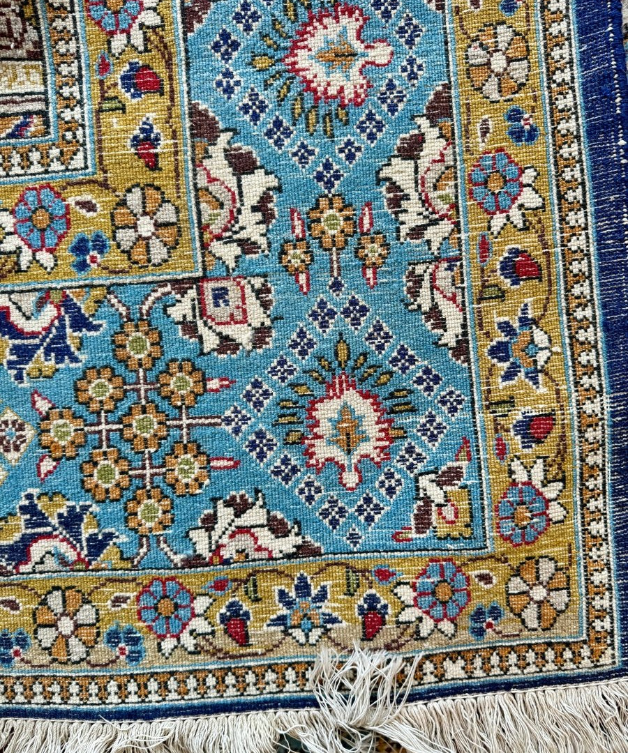 Persian Qum rug close-up with turquoise pattern, floral motifs, and short fringe edge