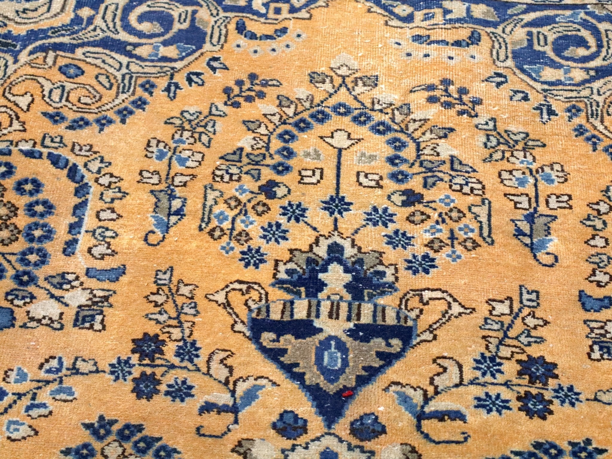 Persian-style rug close-up of blue star and floral motifs on tan background