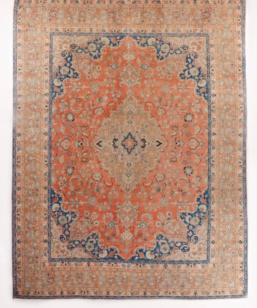 Persian-style rug with coral center medallion and navy corner accents, ornate border
