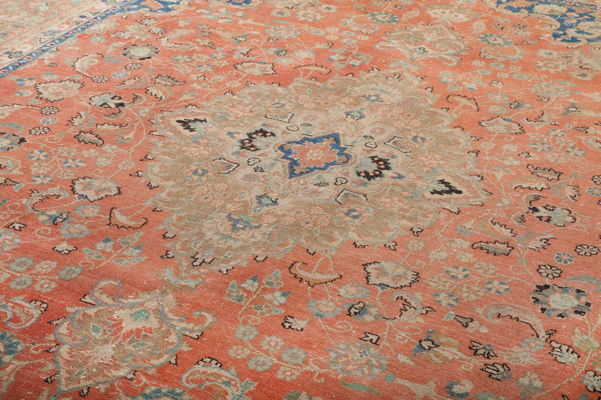 Persian-style rug close view with coral field and small center medallion