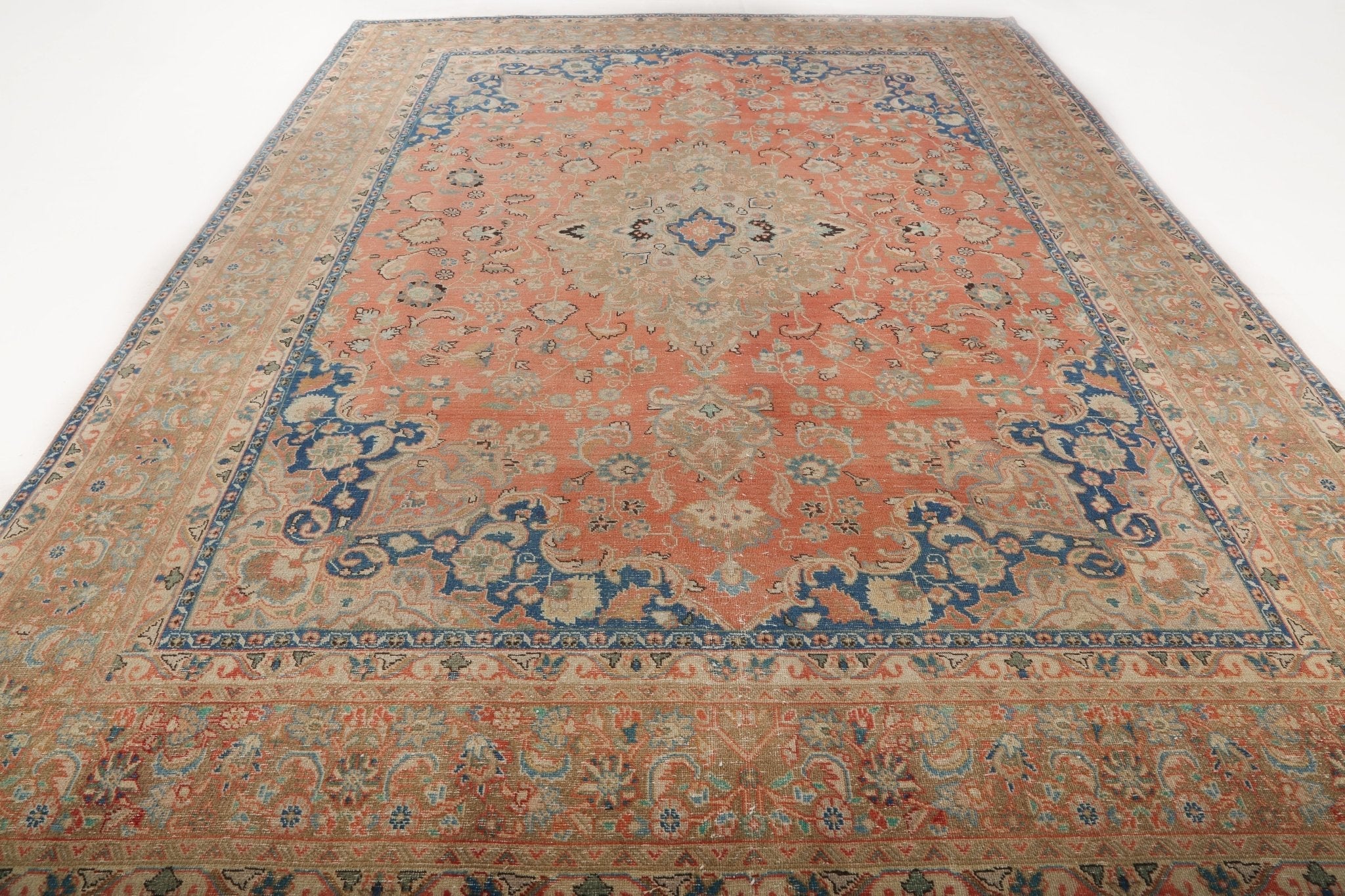 Large Persian-style rug with coral field, navy border, and central medallion