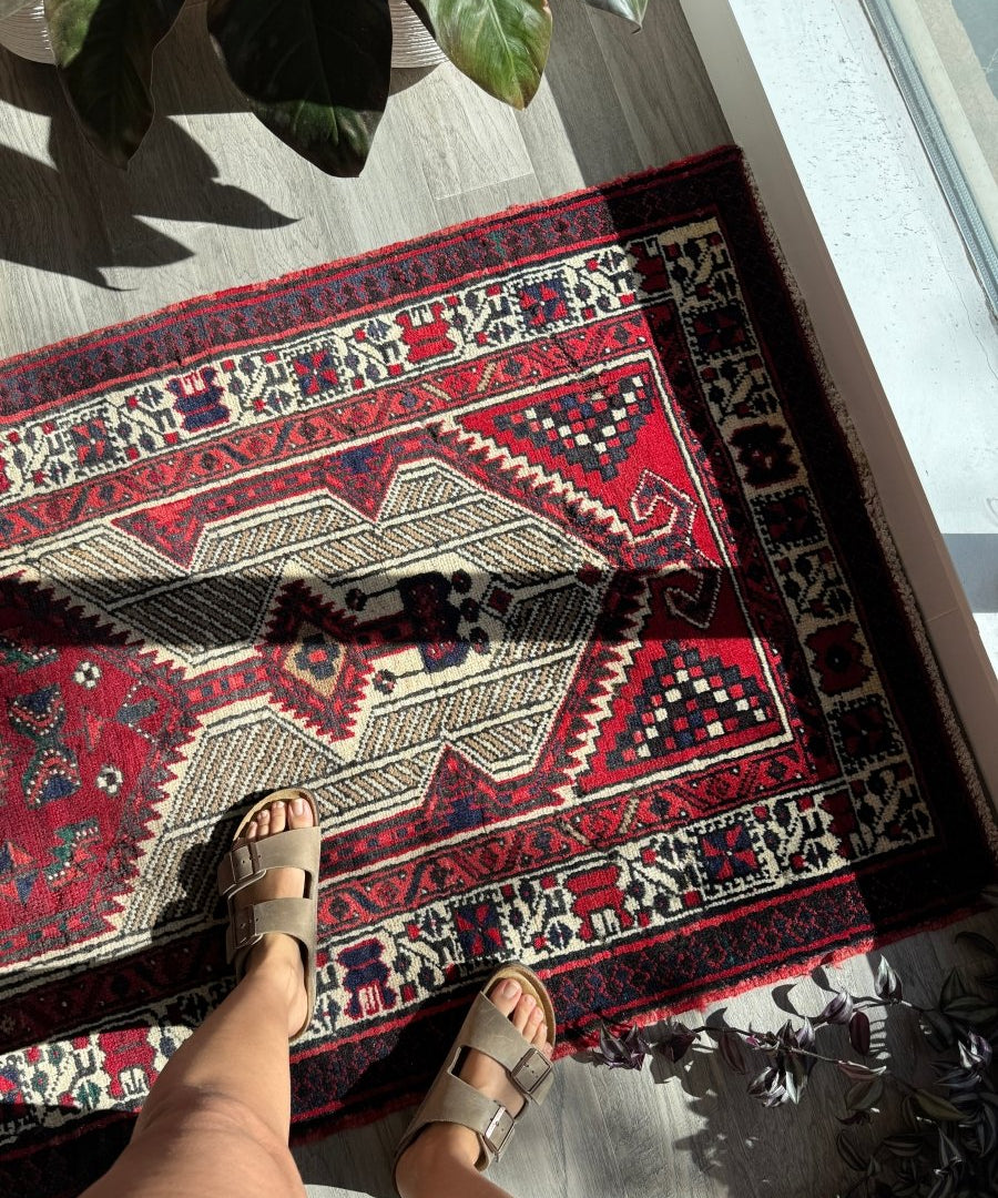 Red and cream Persian-style runner rug with bold border pattern and corner details