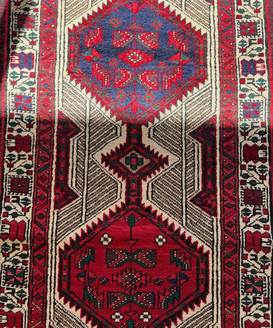 Close-up of Persian-style runner rug with red and teal diamond medallions on cream