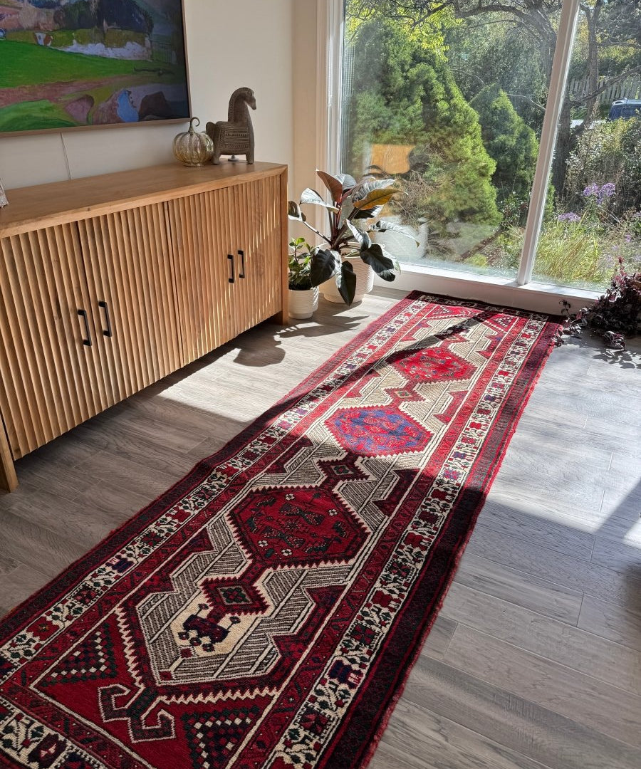 Persian-style runner rug in red, cream, and dark accents with border and center motifs