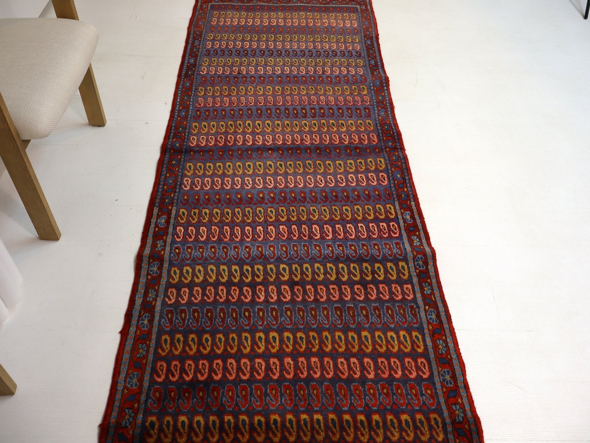 Long runner rug with blue ground and red-orange medallion rows, flat weave pattern.