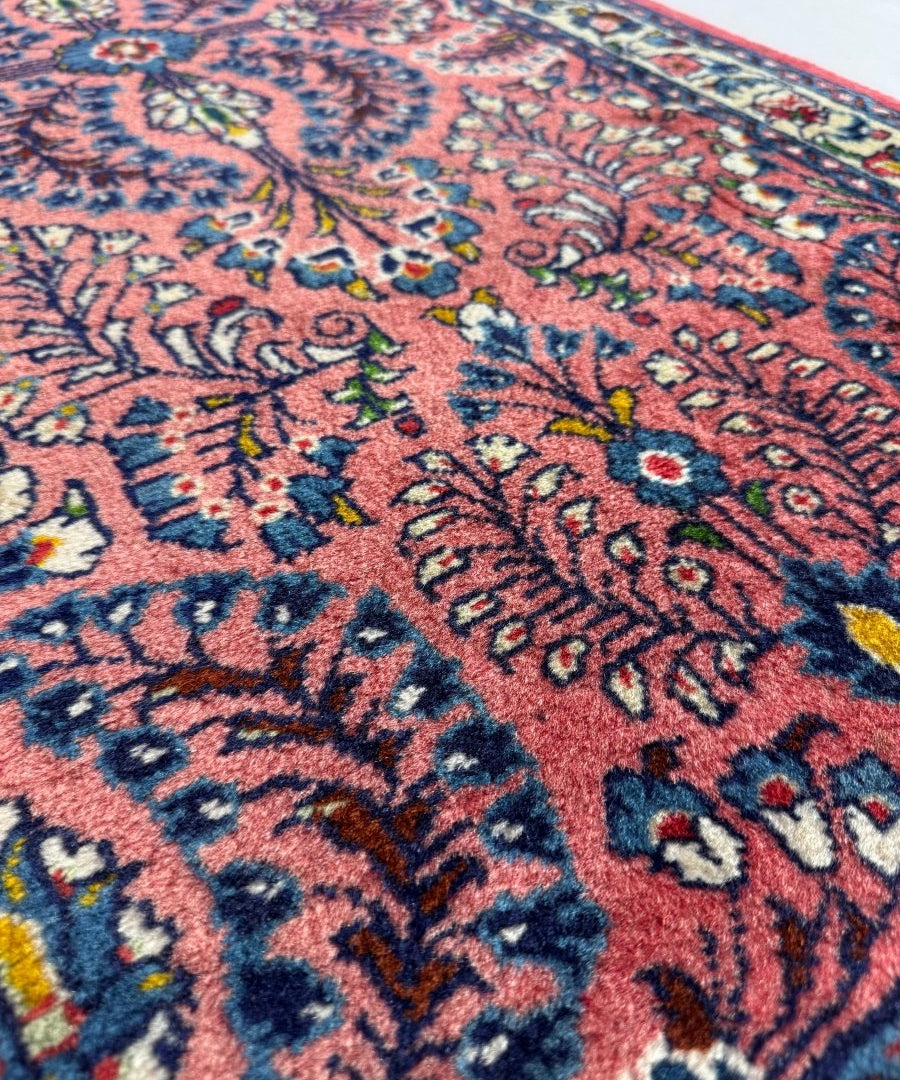Close-up of Persian Sarouk rug pattern with red ground, blue accents, and floral motifs