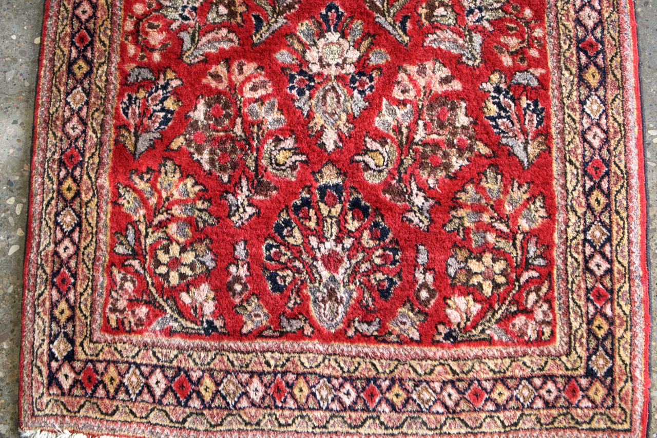 Persian Sarouk rug close-up of red centerpiece with cream and dark vine motifs.