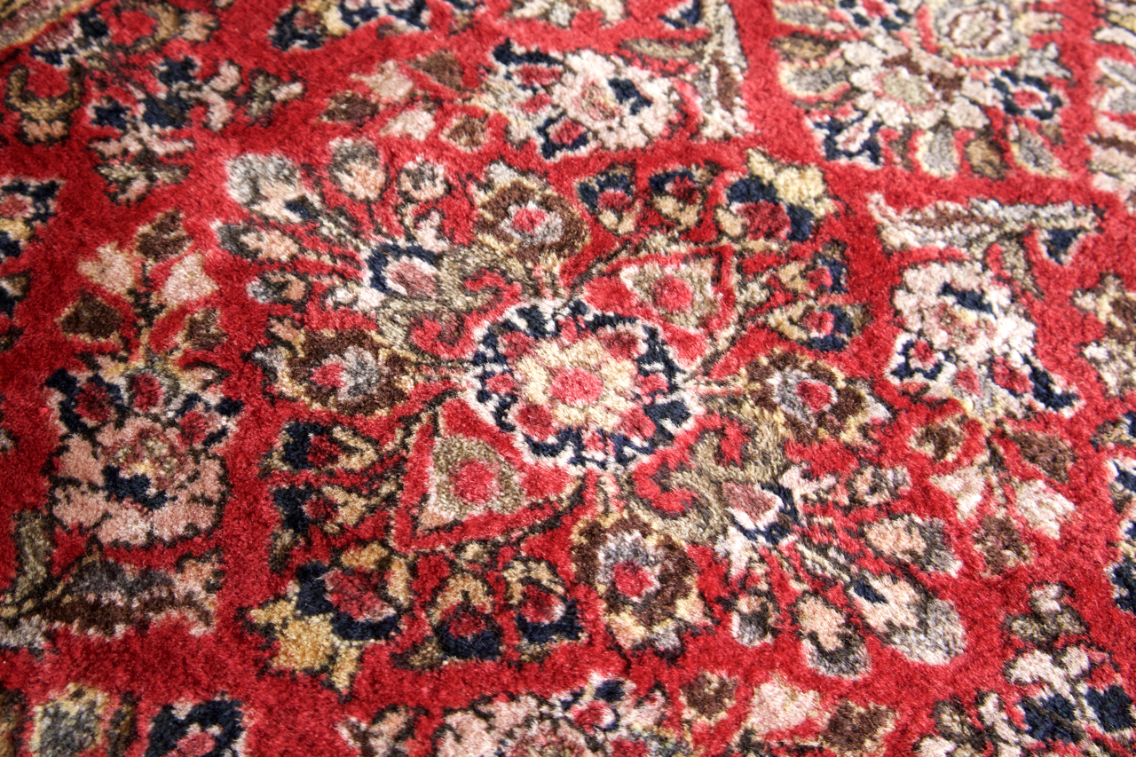 Persian Sarouk rug close-up of red field with cream and dark floral medallions.