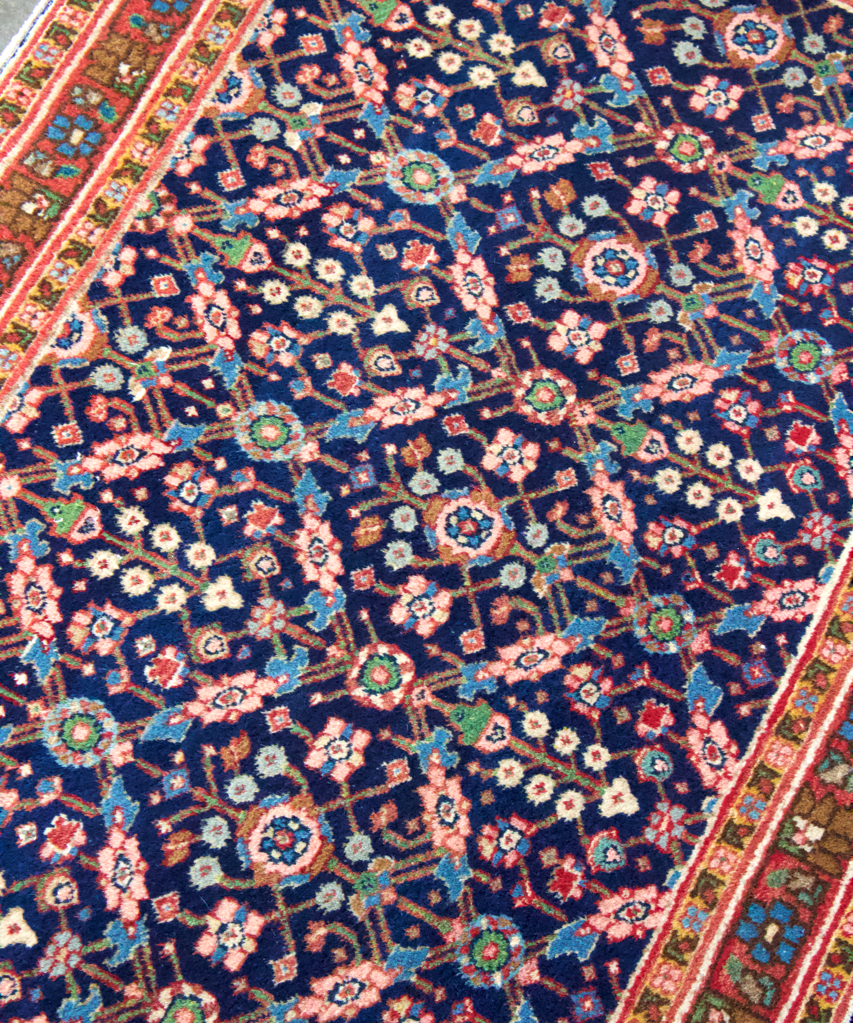 Sarouk rug with deep navy field and multicolor floral geometric motifs, high-contrast border.