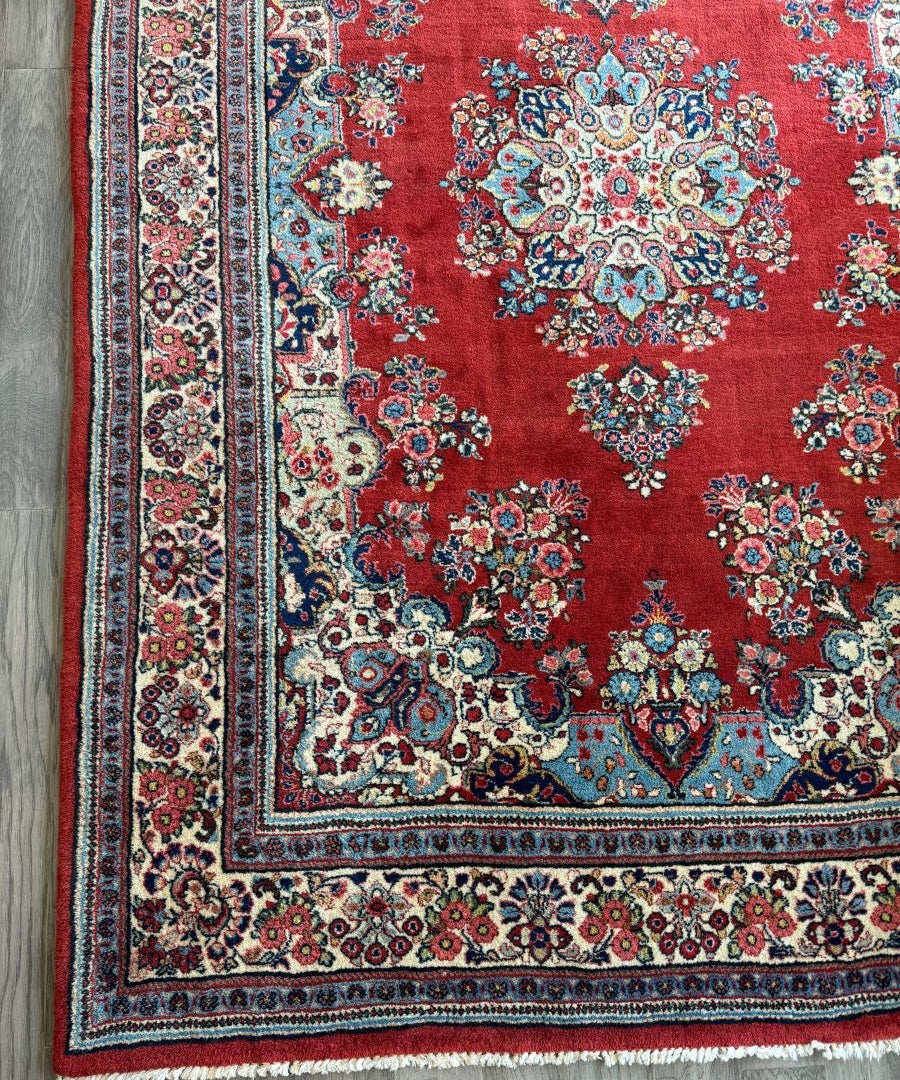 Red Sarouk rug with central floral medallion and multicolor vines, bordered design.