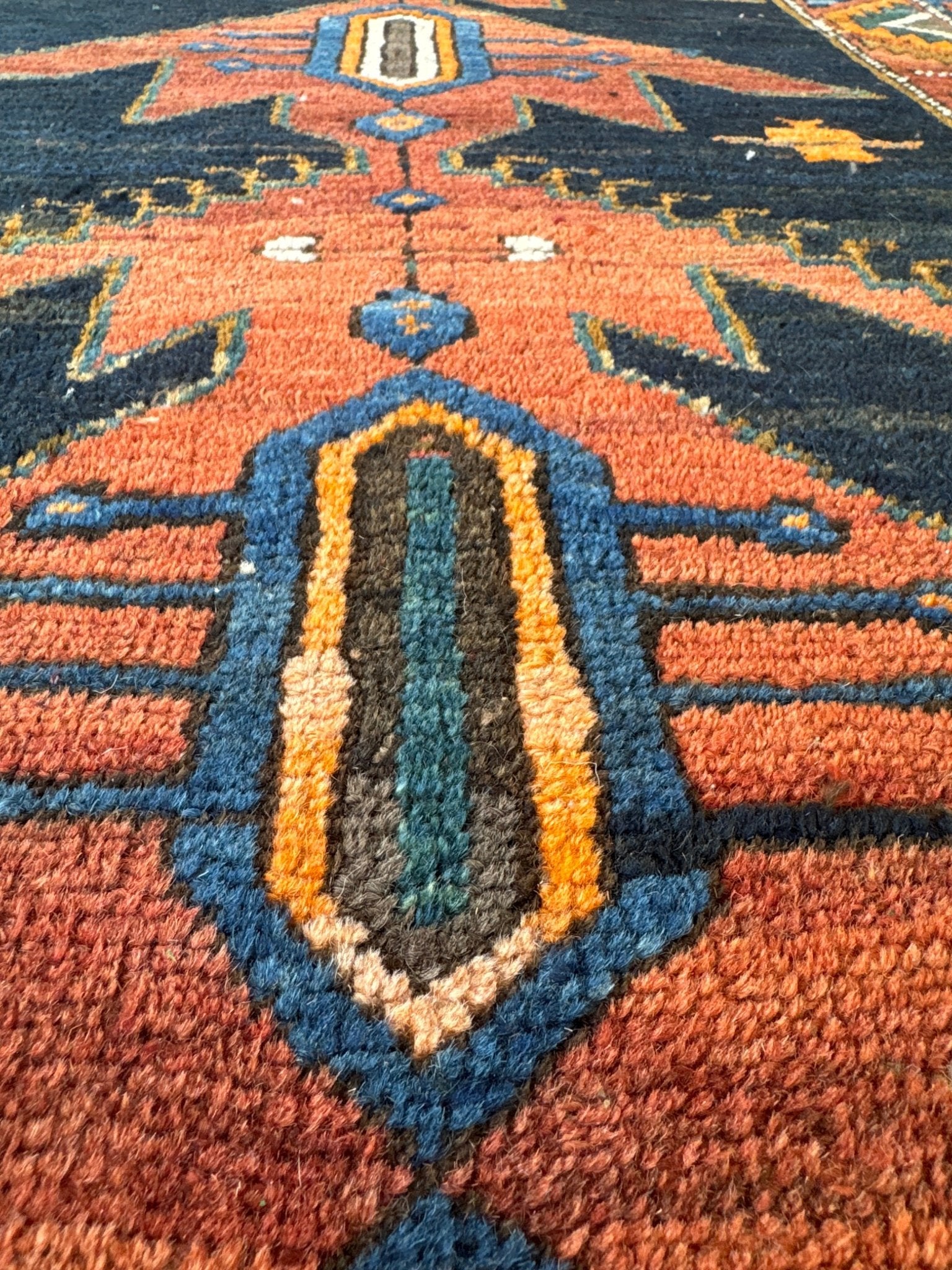 Orange, teal, and navy geometric pattern on Persian runner rug with diamond accents