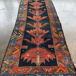Full view of Persian-style runner rug with navy center panel, rust medallion, and borders